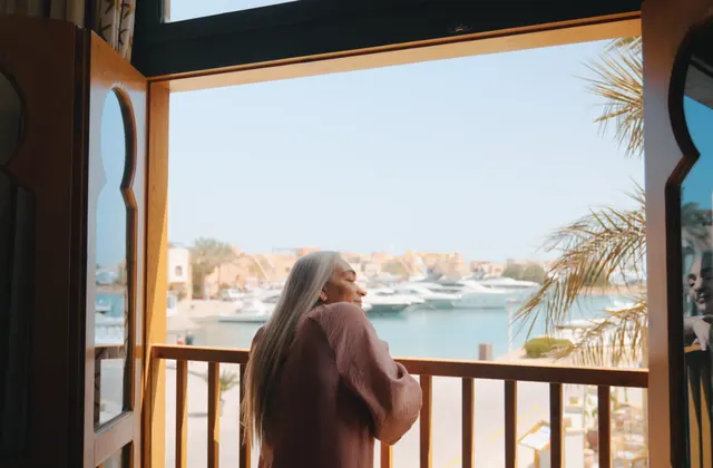 Woman standing on a wooden balcony overlooking a marina with yachts at dusk