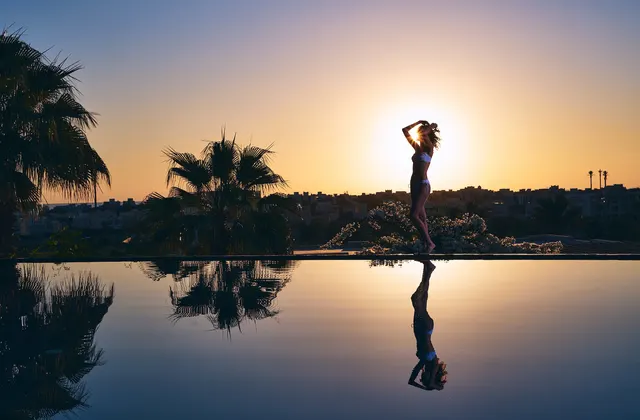 Guest by the infinity pool at sunset at Ancient Sands Golf Resort El Gouna