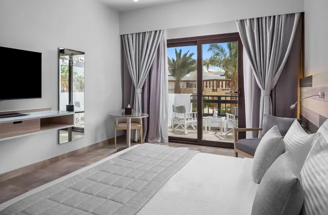 Deluxe Room with king bed, grey bed cover and furnished balcony at Ancient Sands Hotel in El Gouna