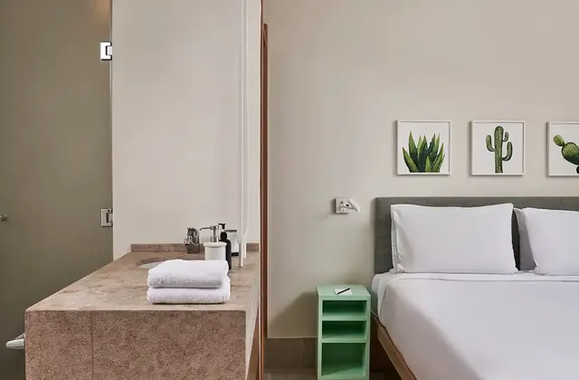 Captains Inn Junior Suite showcasing both the bed and bathroom areas. The bedroom features a comfortable, well-appointed bed with plush linens and decorative pillows, creating a cozy and stylish retreat. The bathroom, visible through an open door or partition, is modern and elegantly designed, with sleek fixtures, a spacious shower or bathtub, and high-quality amenities. The overall decor blends sophistication with functionality, providing a luxurious and relaxing experience.