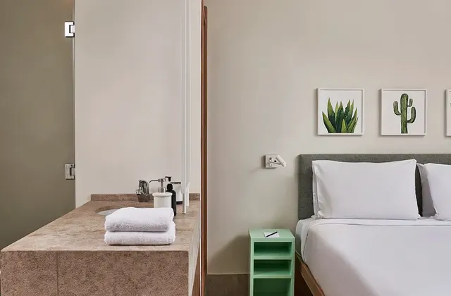 Captains Inn Junior Suite showcasing both the bed and bathroom areas. The bedroom features a comfortable, well-appointed bed with plush linens and decorative pillows, creating a cozy and stylish retreat. The bathroom, visible through an open door or partition, is modern and elegantly designed, with sleek fixtures, a spacious shower or bathtub, and high-quality amenities. The overall decor blends sophistication with functionality, providing a luxurious and relaxing experience.