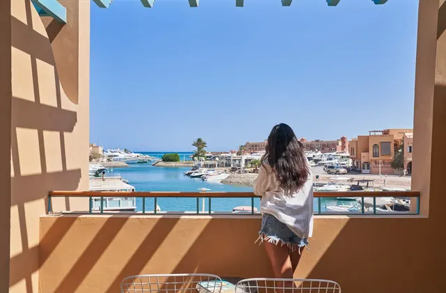 Woman on a terrace overlooking a marina with moored boats and waterfront buildings