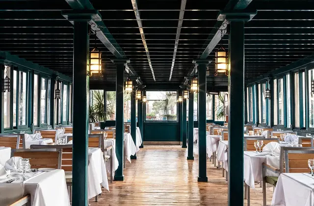 Elegant restaurant interior with dark wood columns and rows of tables set with white linens