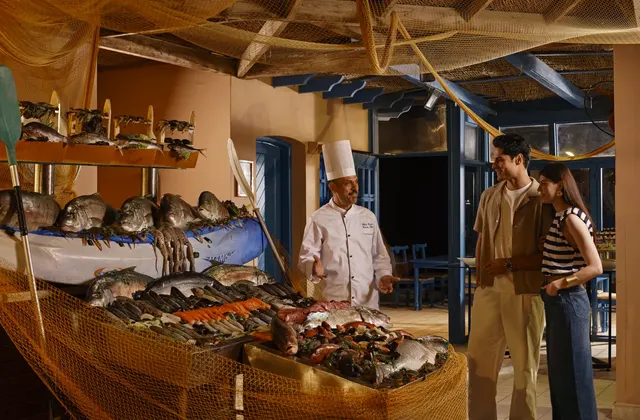Fish counter display at a seafood restaurant with a chef and guests browsing the catch