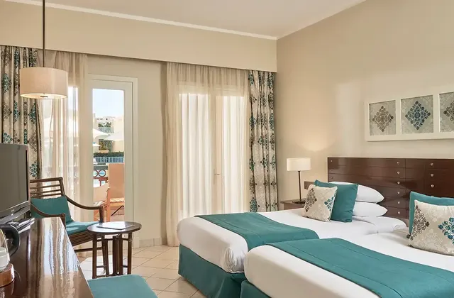 Twin bedroom at Red Sea, Egypt, featuring two single beds with crisp linens, modern decor, and stylish furnishings. The room is bright and inviting, designed for comfort and relaxation, with a warm color palette and ample amenities.