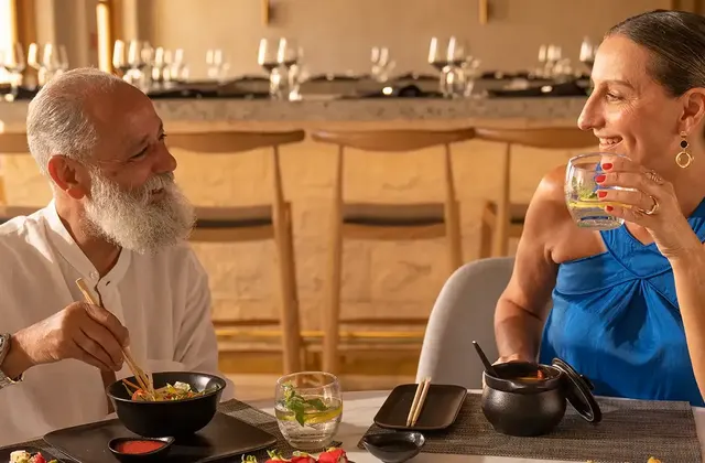 Older couple enjoying a meal together at a restaurant table, one drinking from a glass
