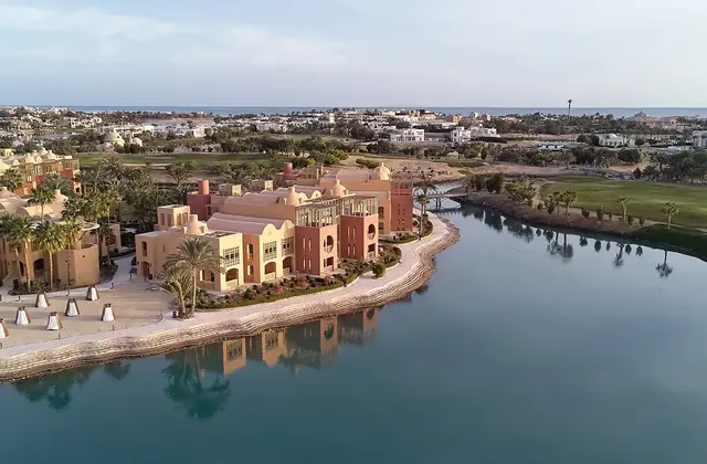 Aerial view of a resort building on a lagoon peninsula surrounded by a golf course and palm trees