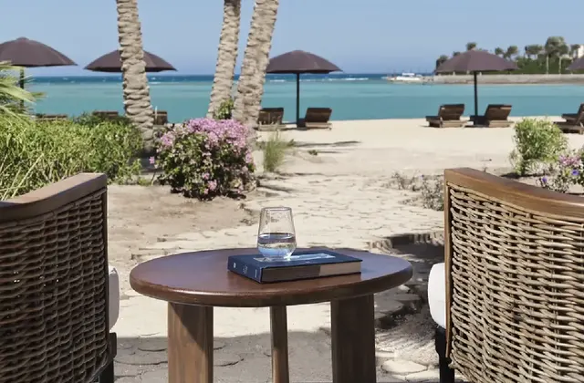 Seaside sitting area on the beach with comfortable chairs and tables, overlooking the sea and clear blue sky.