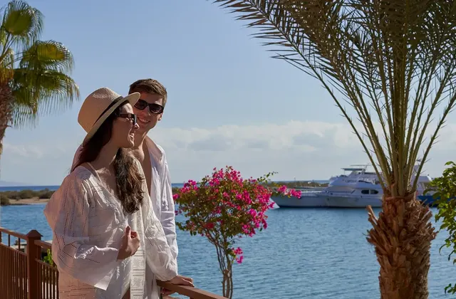 A couple shares a romantic moment framed by the expansive sea and a luxurious yacht in the background, capturing the essence of serene beauty and tranquility.