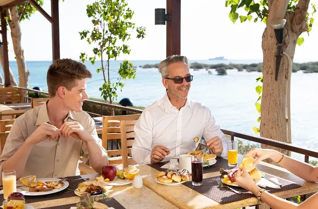 Ocean-view terrace at Oceana Restaurant, with a group of people enjoying their meal together.