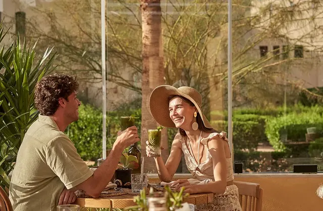 A couple enjoying the dining experience at The Three Corners Rihana Resort. They are seated at an elegantly set table with drinks. The stylish and inviting ambiance enhances their dining experience.