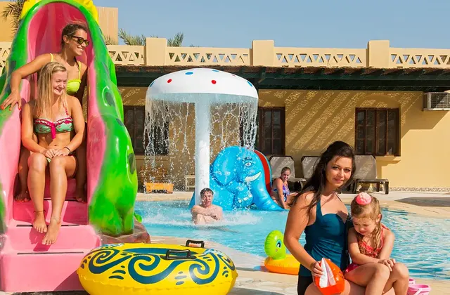Families and kids enjoying the pool area, with children playing on the water slides and people relaxing around the pool. The vibrant and lively scene highlights a fun and engaging atmosphere for all ages.